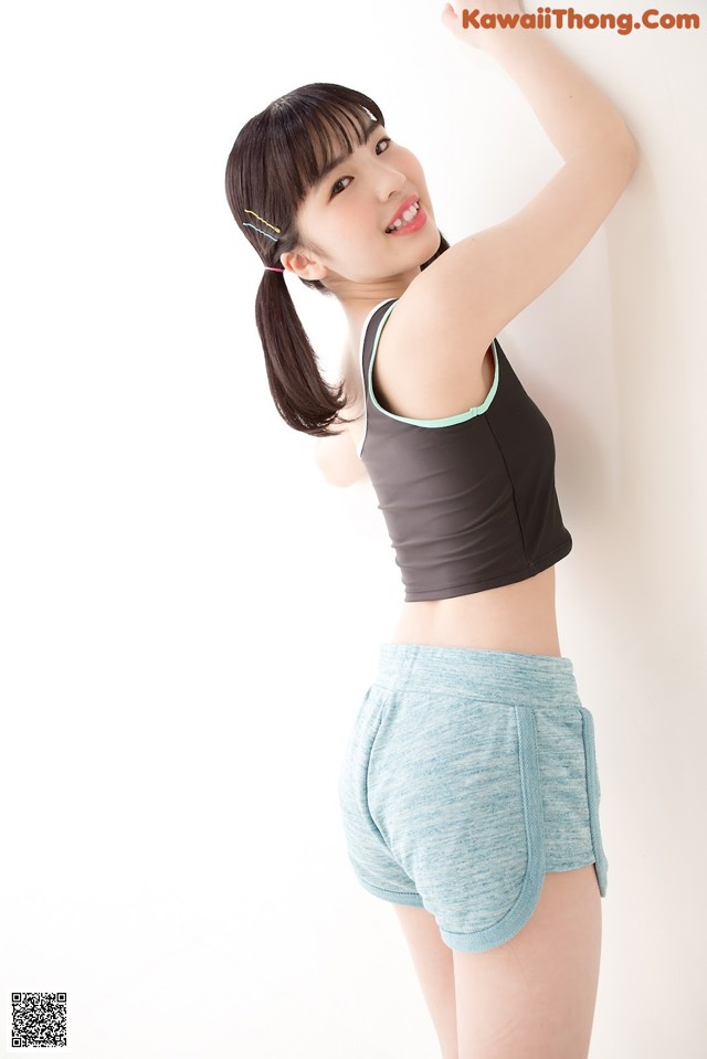 A woman in a black top and blue shorts posing for a picture.