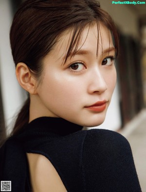 A woman sitting on the ground wearing a brown sweater.