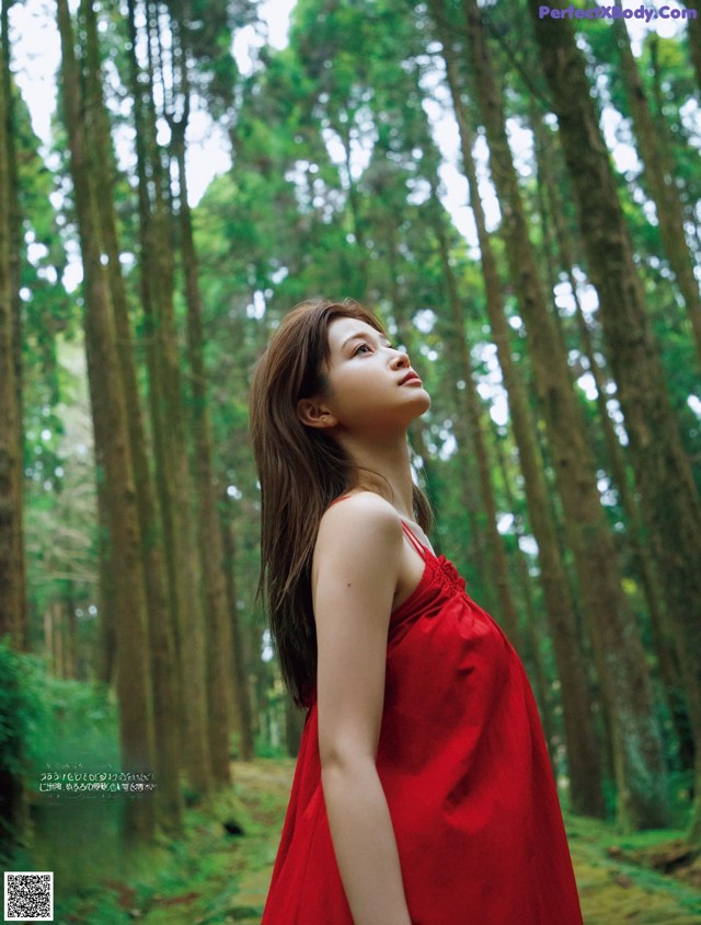 A woman in a red dress standing in a forest.