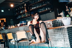 A woman in a black lingerie sitting at a bar.