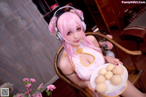 A woman with pink hair wearing headphones and holding a plate of food.