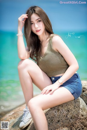 A woman sitting on a rock by the ocean.