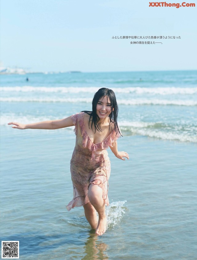 A woman in a pink dress is standing in the water.