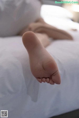 A woman in black stockings and high heels is laying on a bed.