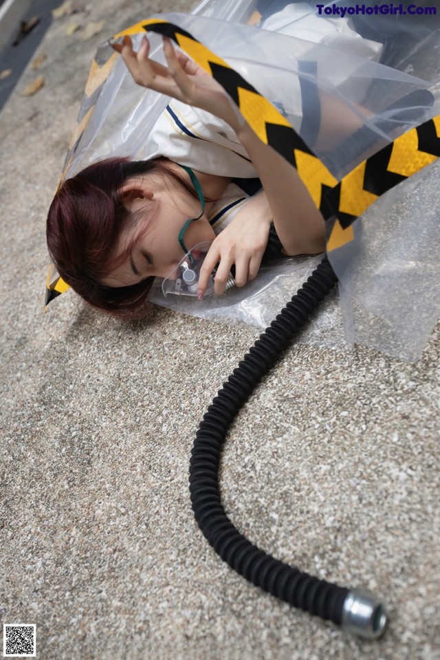 A woman laying on the ground with a hose attached to her head.