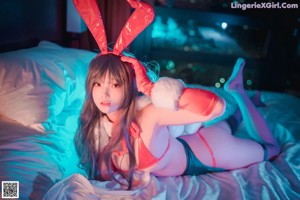 A woman in a bunny costume sitting on a bed.