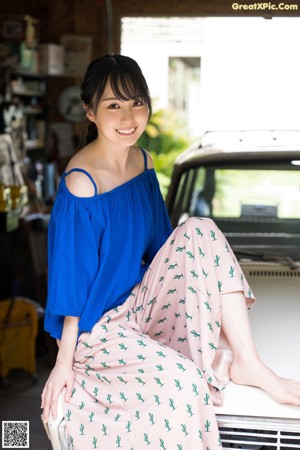 A woman sitting on a stool holding two lemons.