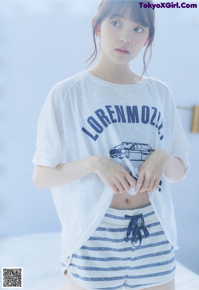 A woman wearing a white shirt and blue and white striped shorts.