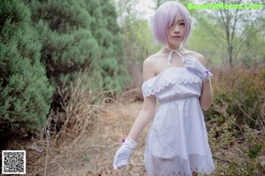 A woman in a white dress standing in the middle of a road.