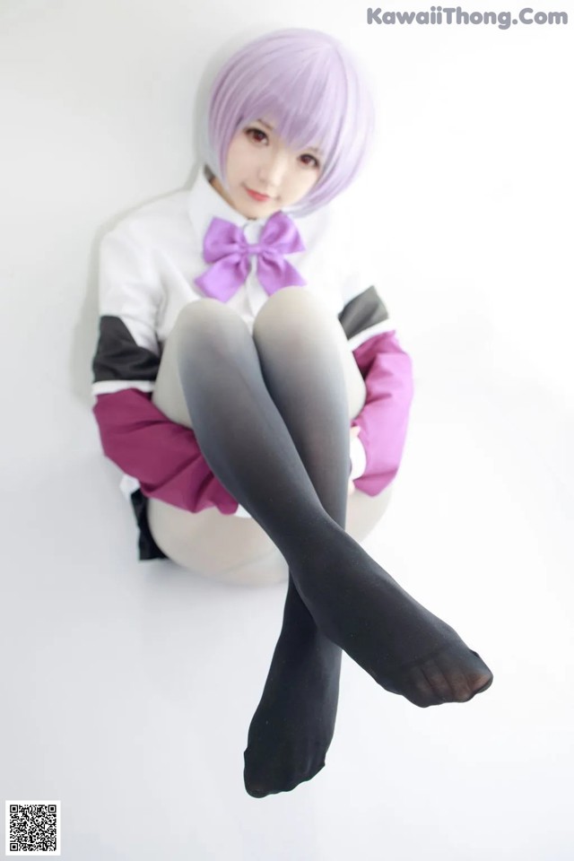 A woman with purple hair sitting on a white surface.
