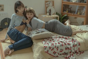 A couple of women sitting on top of a couch.