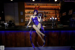 A woman in a bunny costume sitting on a bar.