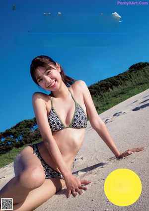 A woman in a gray bikini leaning against a wall.