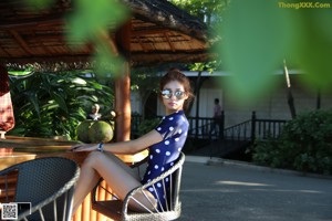 A woman in a bathing suit sitting on lounge chairs by a pool.