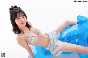 A young girl sitting on top of a blue toy car.