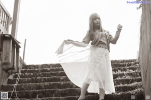 A woman in a blue sweater and a white skirt posing for a picture.