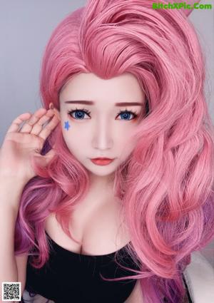 A woman with long pink hair and blue eyes posing for a picture.