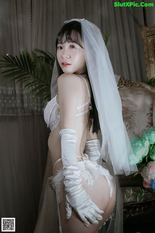 A woman in a wedding dress and gloves posing for a picture.