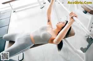A woman sitting on a bench in a gym.