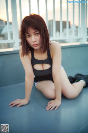 A woman in a gray thong sitting on a wooden table.