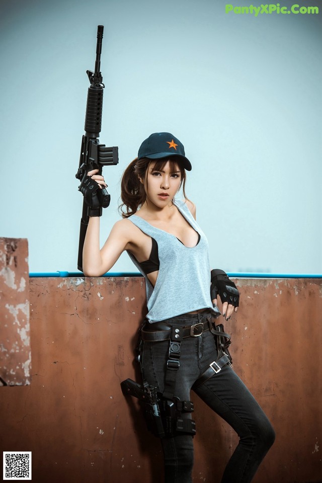 A woman holding a rifle and wearing a hat.