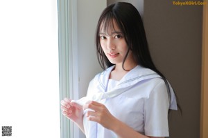 A woman in a white shirt and white panties sitting on the floor.