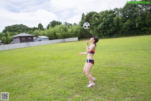 A woman in a bikini playing volleyball in a field.