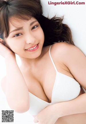 A woman in a purple bra and panties sitting on a bed.