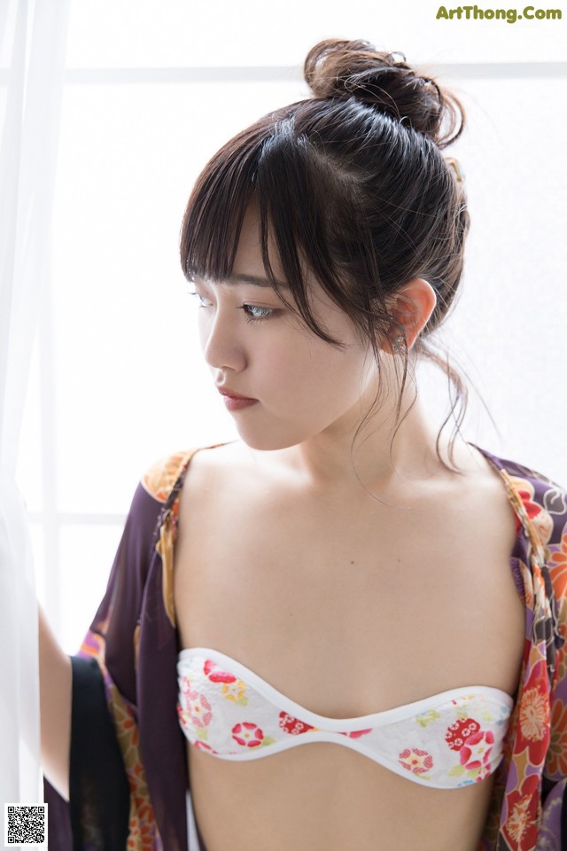 A woman in a kimono looking out a window.