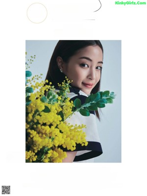 A woman standing in front of a wall of paper flowers.